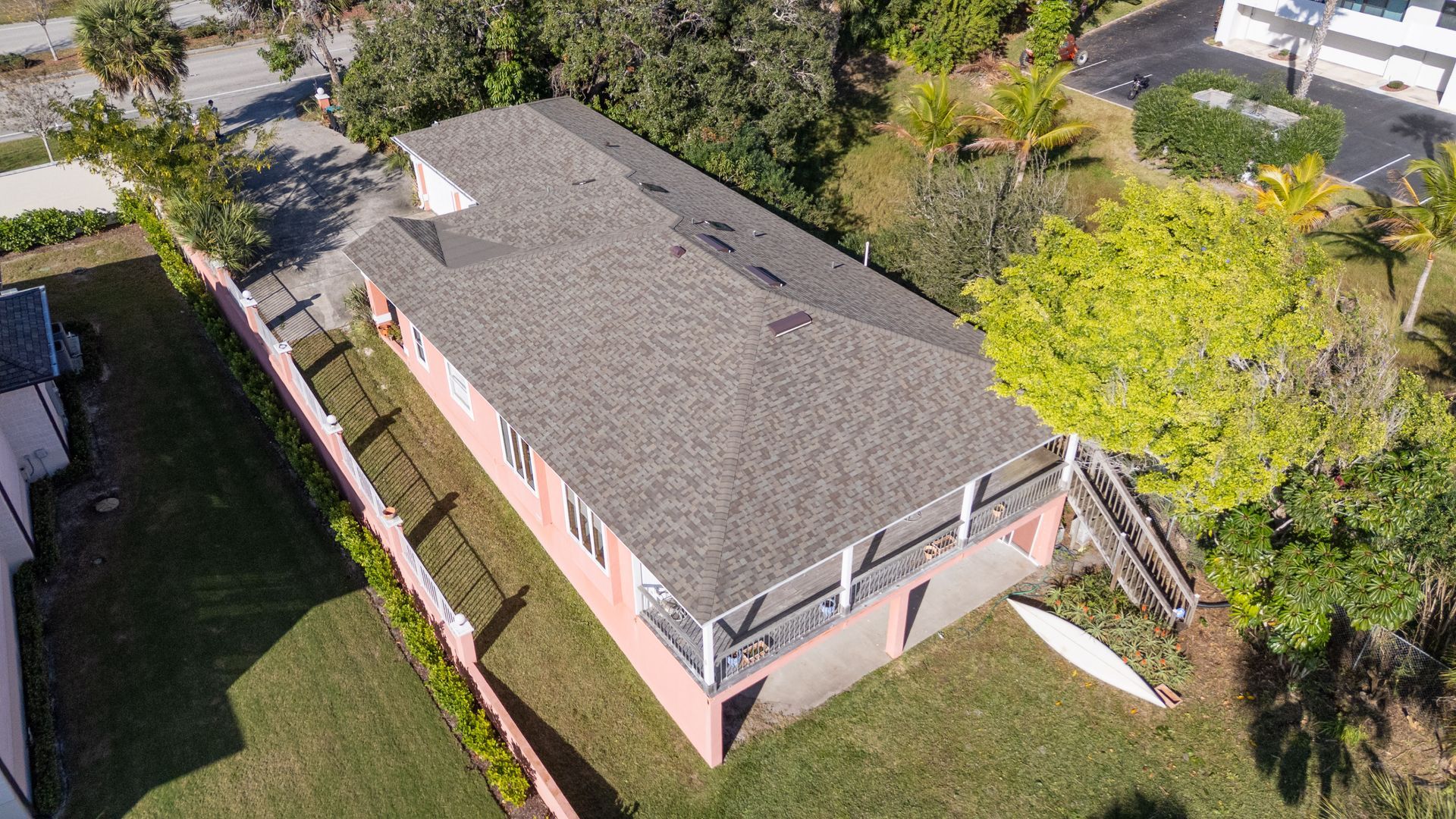 A top-down aerial view of a gray-roofed residential house with a central open-air courtyard and surrounding palm trees.