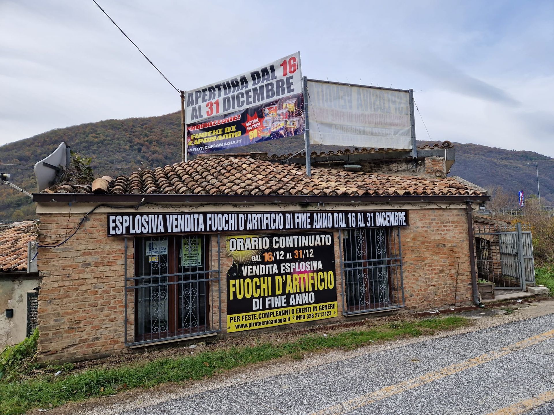 Edificio in pietra a bordo strada con striscioni e cartelli di protesta sotto un cielo nuvoloso.