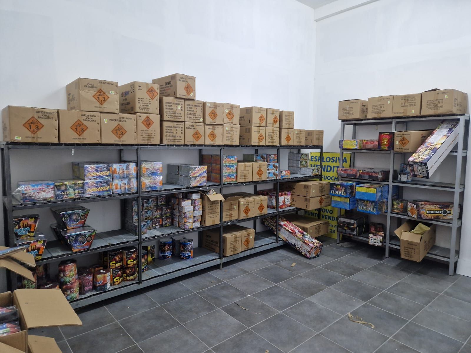 Magazzino con scaffali metallici pieni di scatole di cartone e vari articoli imballati.