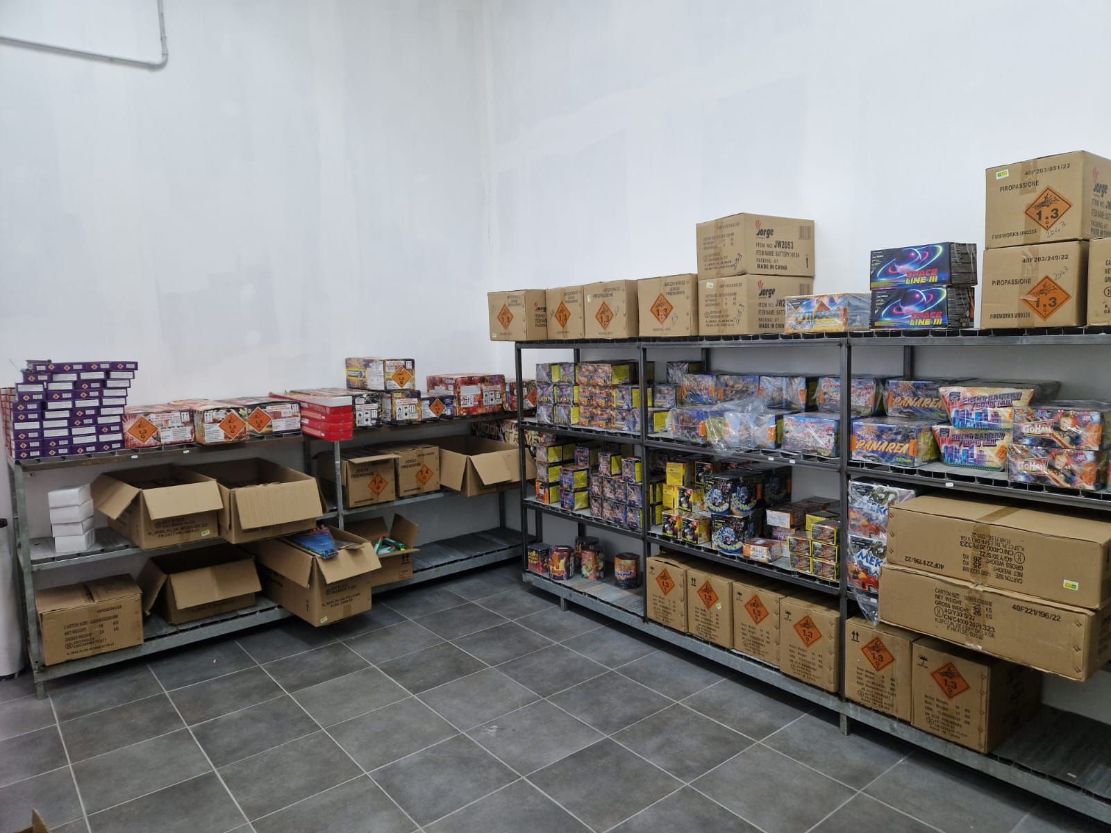 Scaffali pieni di snack confezionati in un piccolo magazzino con pavimento piastrellato.