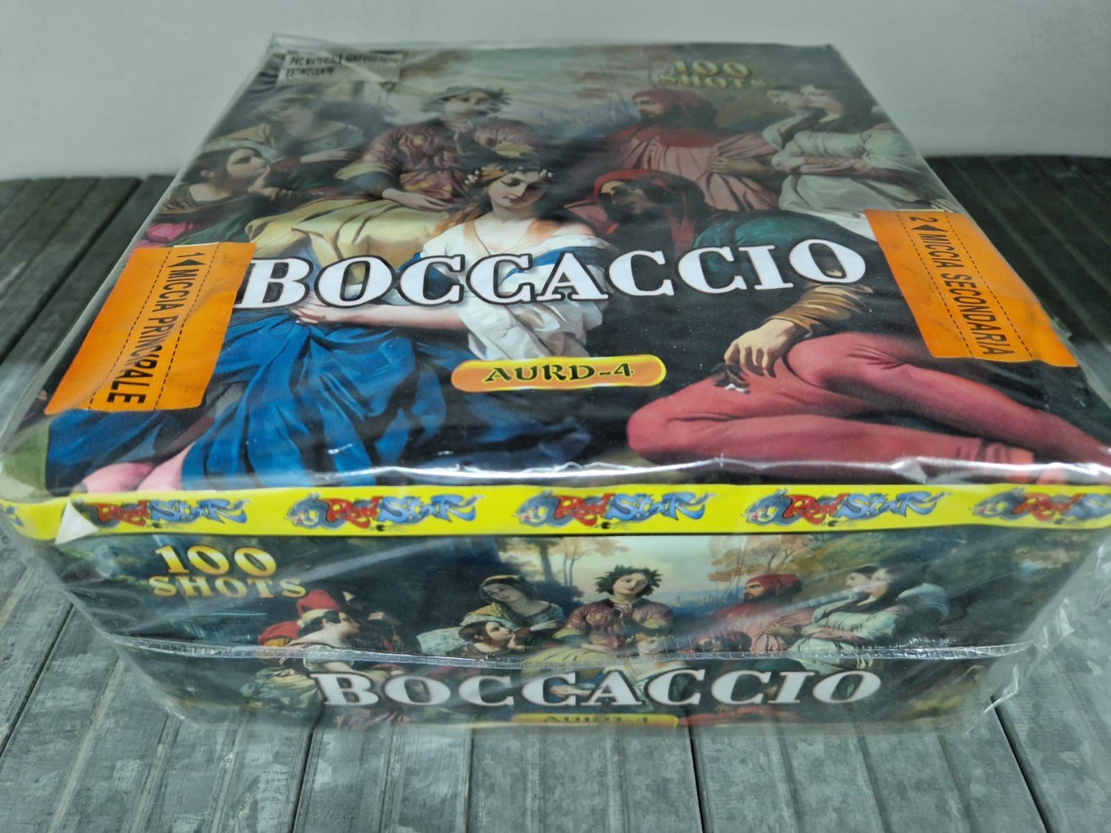 Set di gioco a tema Boccaccio in scatola con copertina illustrata ed etichette giallo brillante su un tavolo