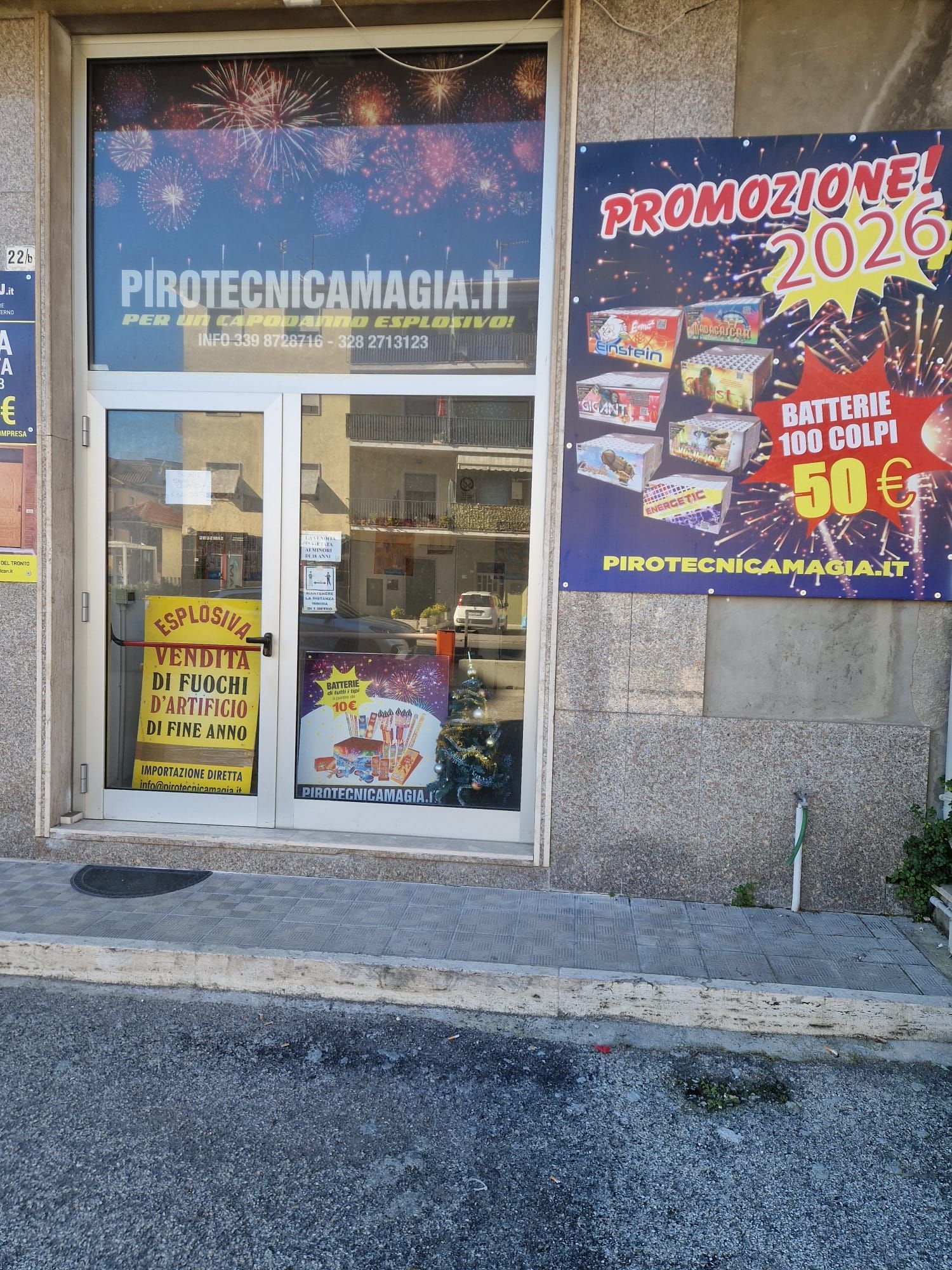 Vetrina di ProtecniCaccia.it con porta a vetri e colorato poster di saldi “Promozione 2026” in italiano
