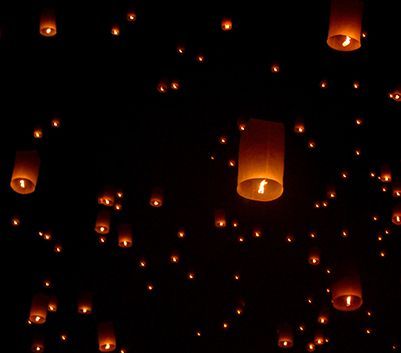 Lanterna volante arancioni e luminose che fluttuano contro un cielo notturno buio