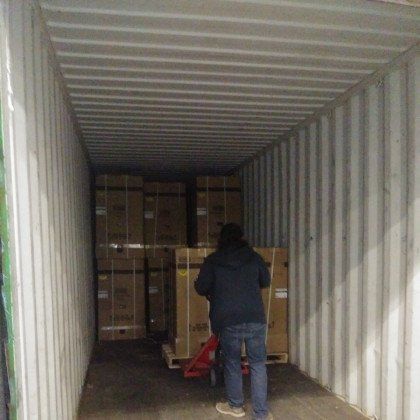 Person using a pallet jack to load boxes into a shipping container.