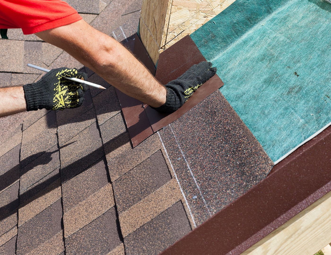 A man is measuring a roof with a tape measure.