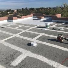 A roof with a bucket of paint and a roll of tape on it.