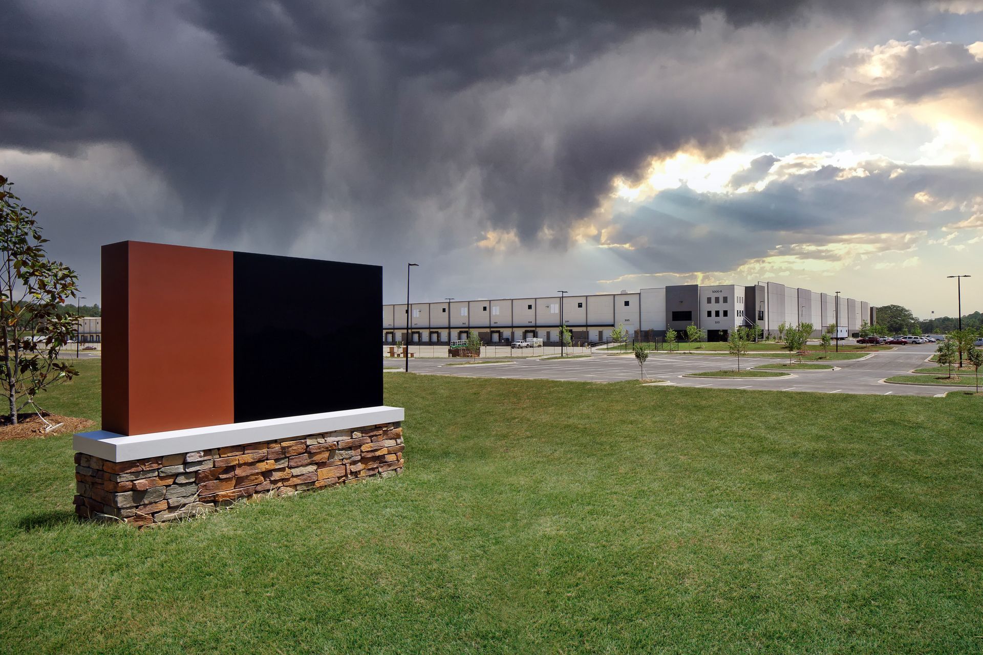 A sign in front of a warehouse, an impending storm in the distance.