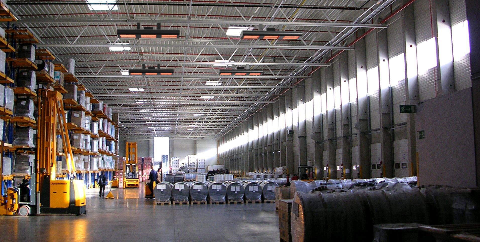 Warehouse aisle with stacked pallets and forklifts under bright overhead lights
