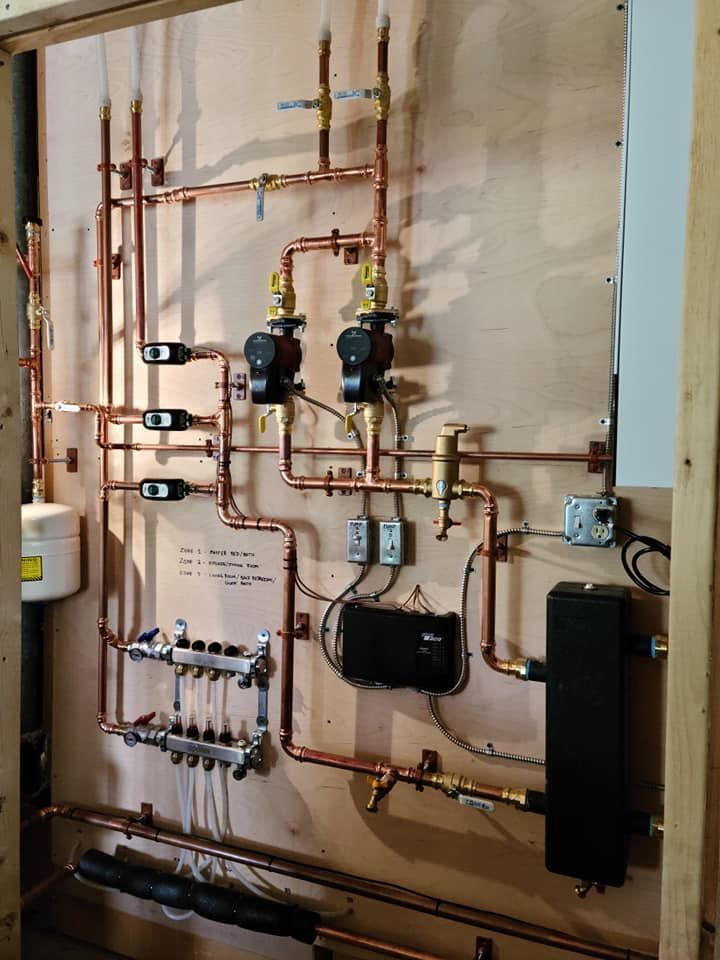 Copper pipes and heating components mounted on a wooden board.