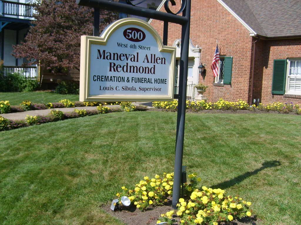 Sign for Maneval Allen Redmond, a funeral home, with brick building in background.