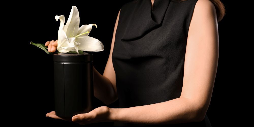 Woman holding a memorial urn with a white lily in Pharr, TX.