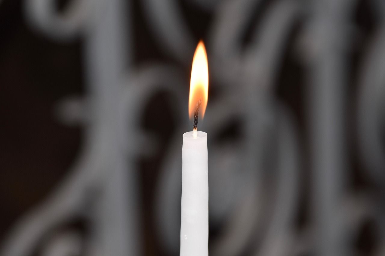 Single glowing candle in dark surroundings representing devotion, reflection, and quiet tribute.