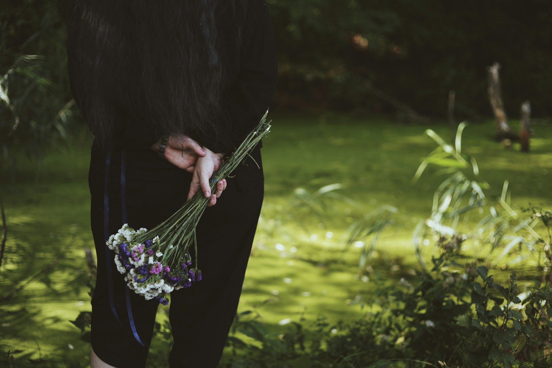Woman holding a bouquet of colorful flowers in her hands expressing care and remembrance.