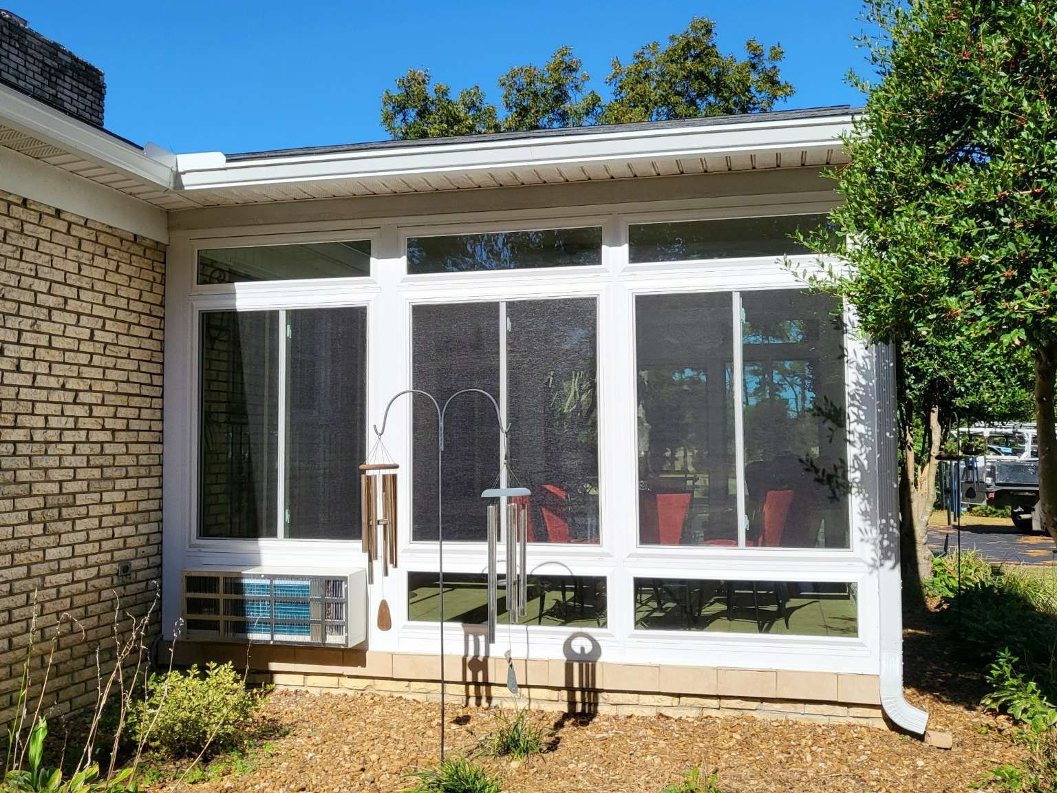 A screened in porch with a brick building in the background