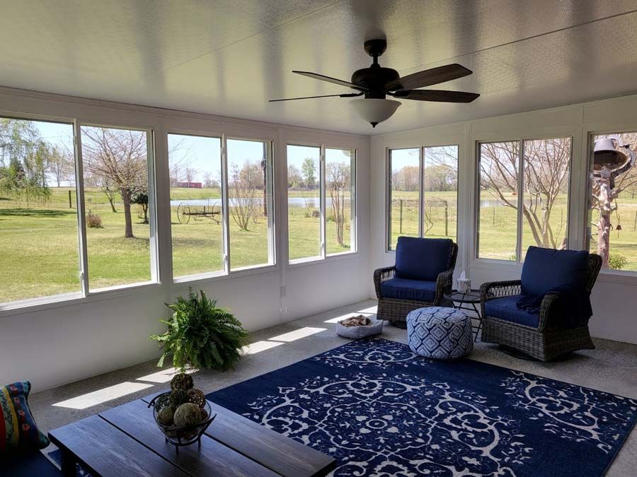 A screened in porch with a lot of windows and a ceiling fan
