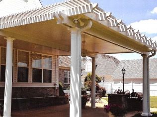 Covered patio with white columns, attached to a house with a pergola roof.