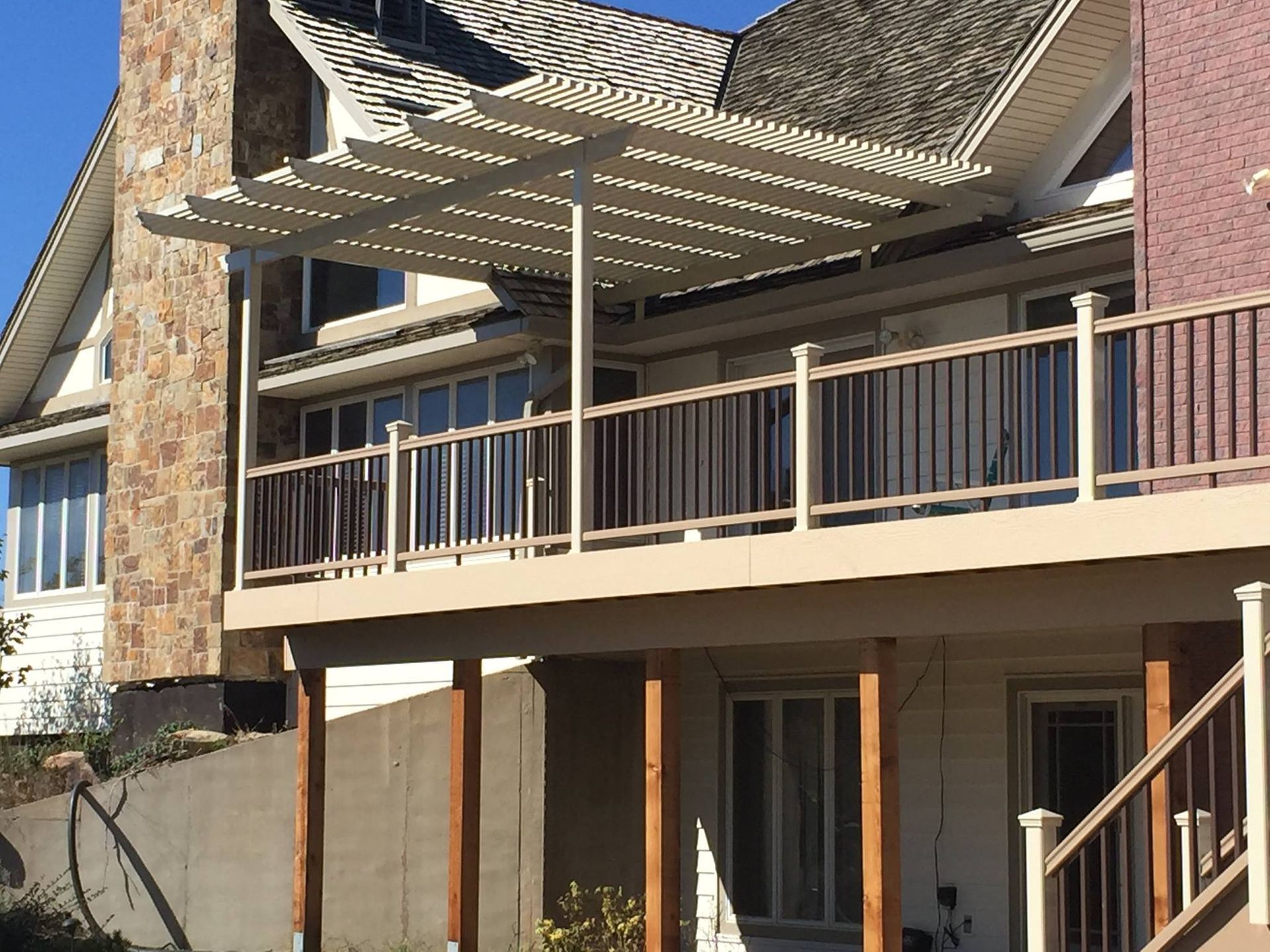 A patio with a pergola and white pillars in front of a house
