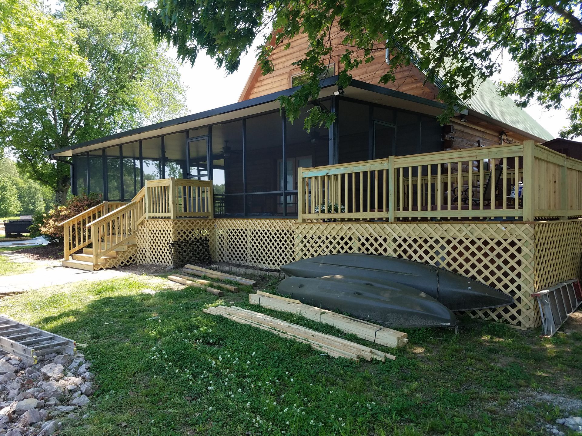 A screened-in porch and deck on a house. Two kayaks rest on the deck's lower level.