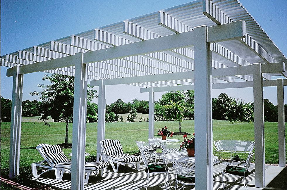 A white pergola with a table and chairs underneath it