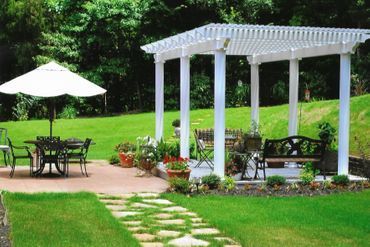 A white pergola with tables and chairs underneath it