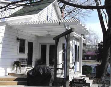 A white house with a covered porch and a grill