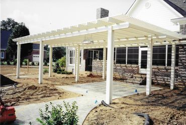 A house with a white pergola in front of it