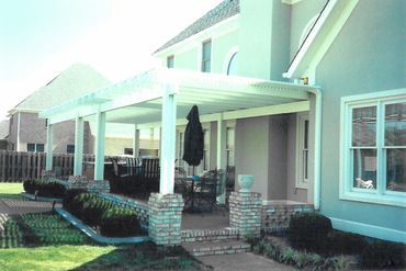 A white house with a large porch and a black umbrella