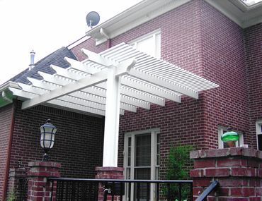 A brick house with a white pergola on the front porch