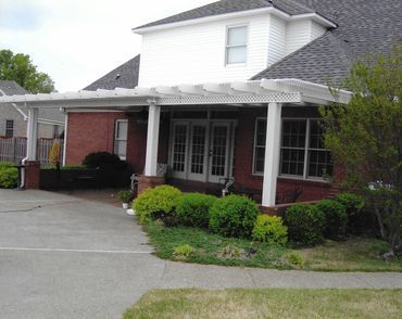 A brick house with a white pergola on the front porch
