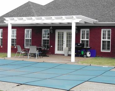 A red brick house with a white pergola over a pool