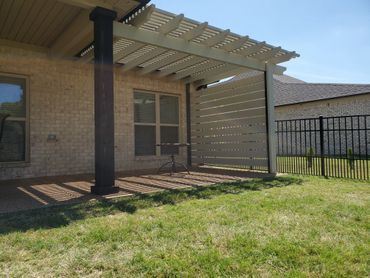 A patio with a pergola in the backyard of a house