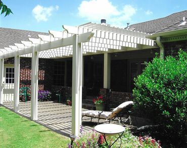 A white pergola is in the backyard of a house