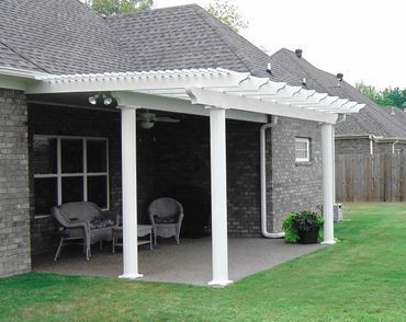 There is a pergola on the back of a brick house