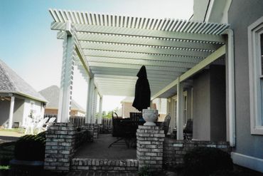 A patio with a pergola and a black umbrella