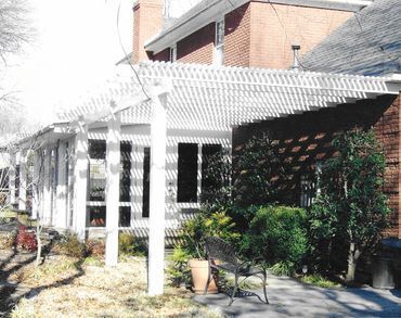 A brick house with a white pergola in front of it