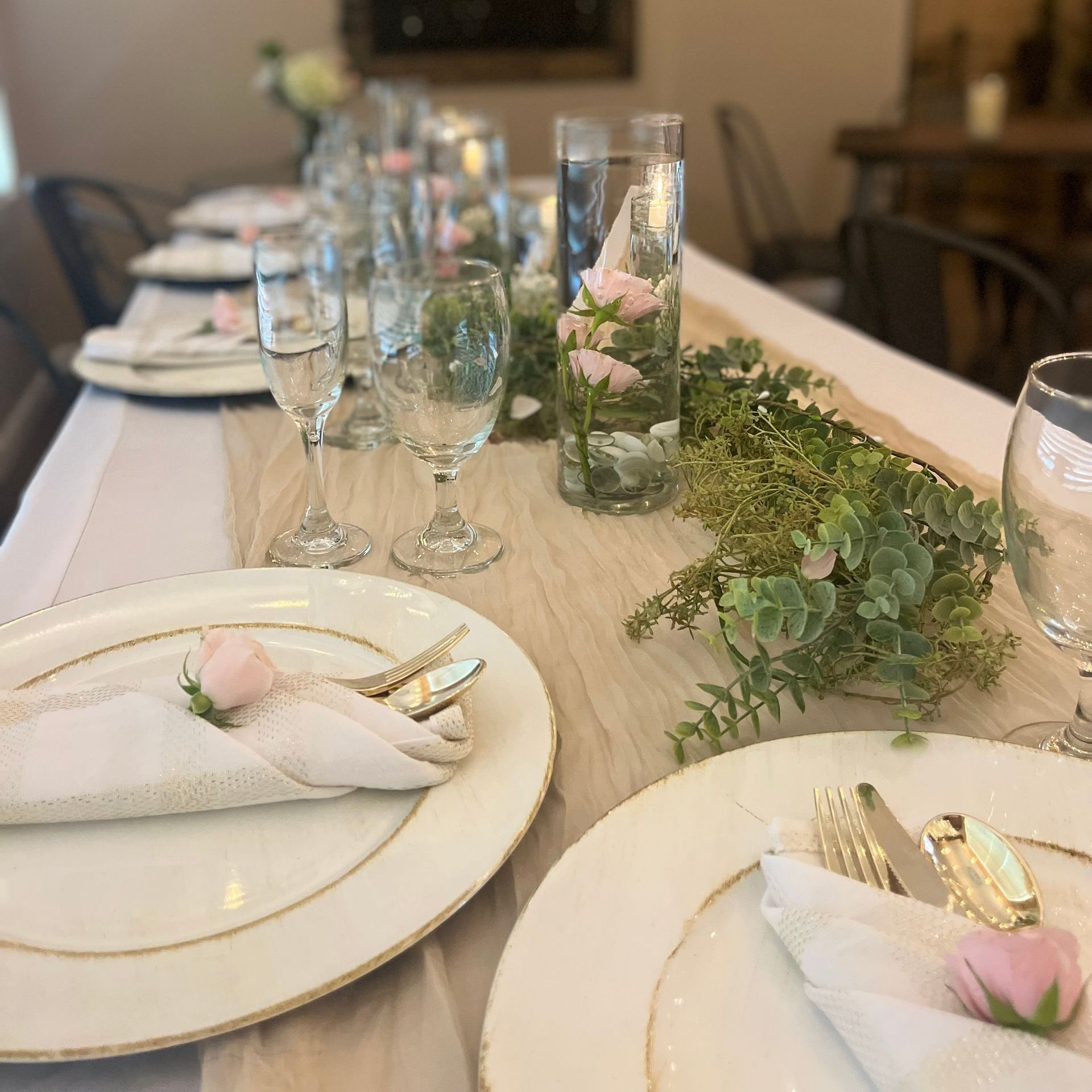 Formal table setting with white plates, glassware, and floral centerpieces.