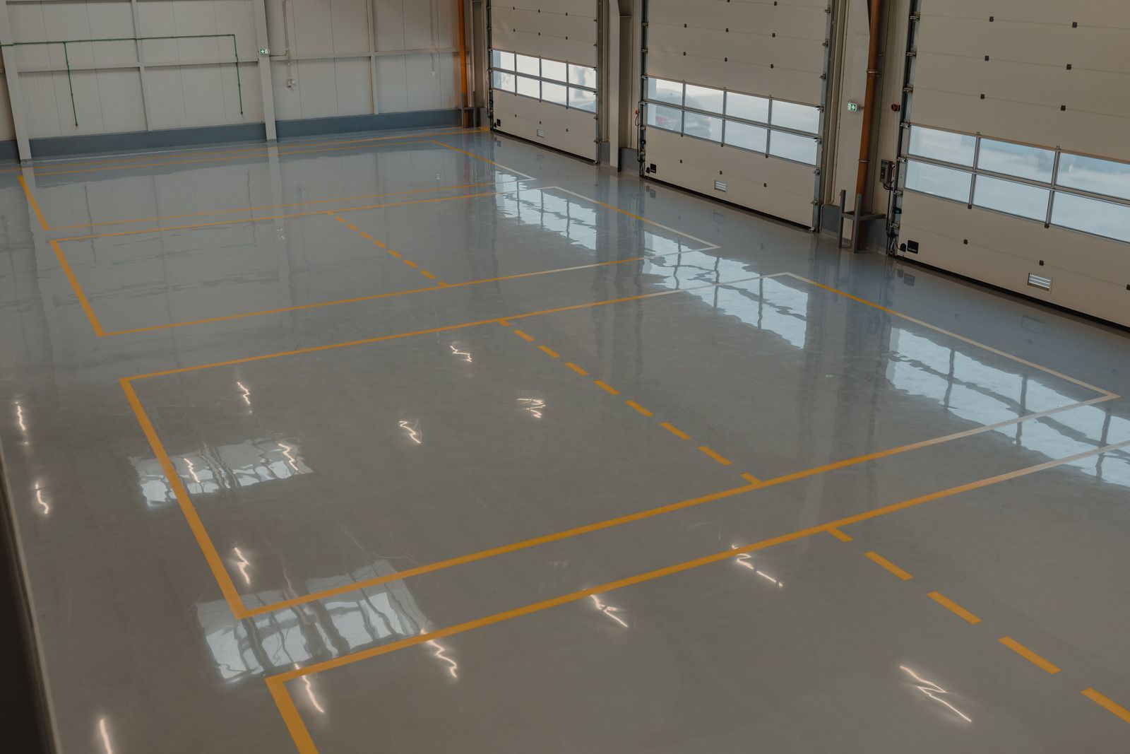 A man is painting a concrete floor with a roller.