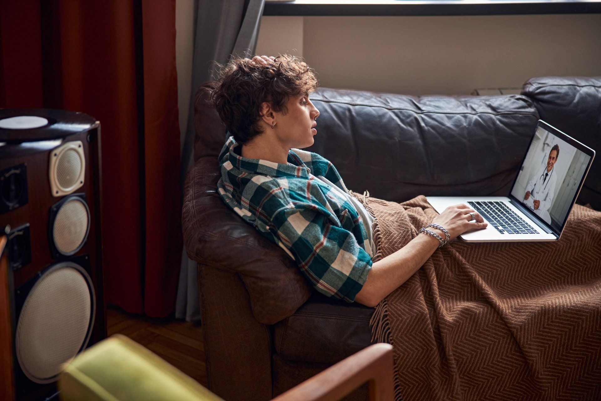 A man is sitting on a couch using a laptop computer.
