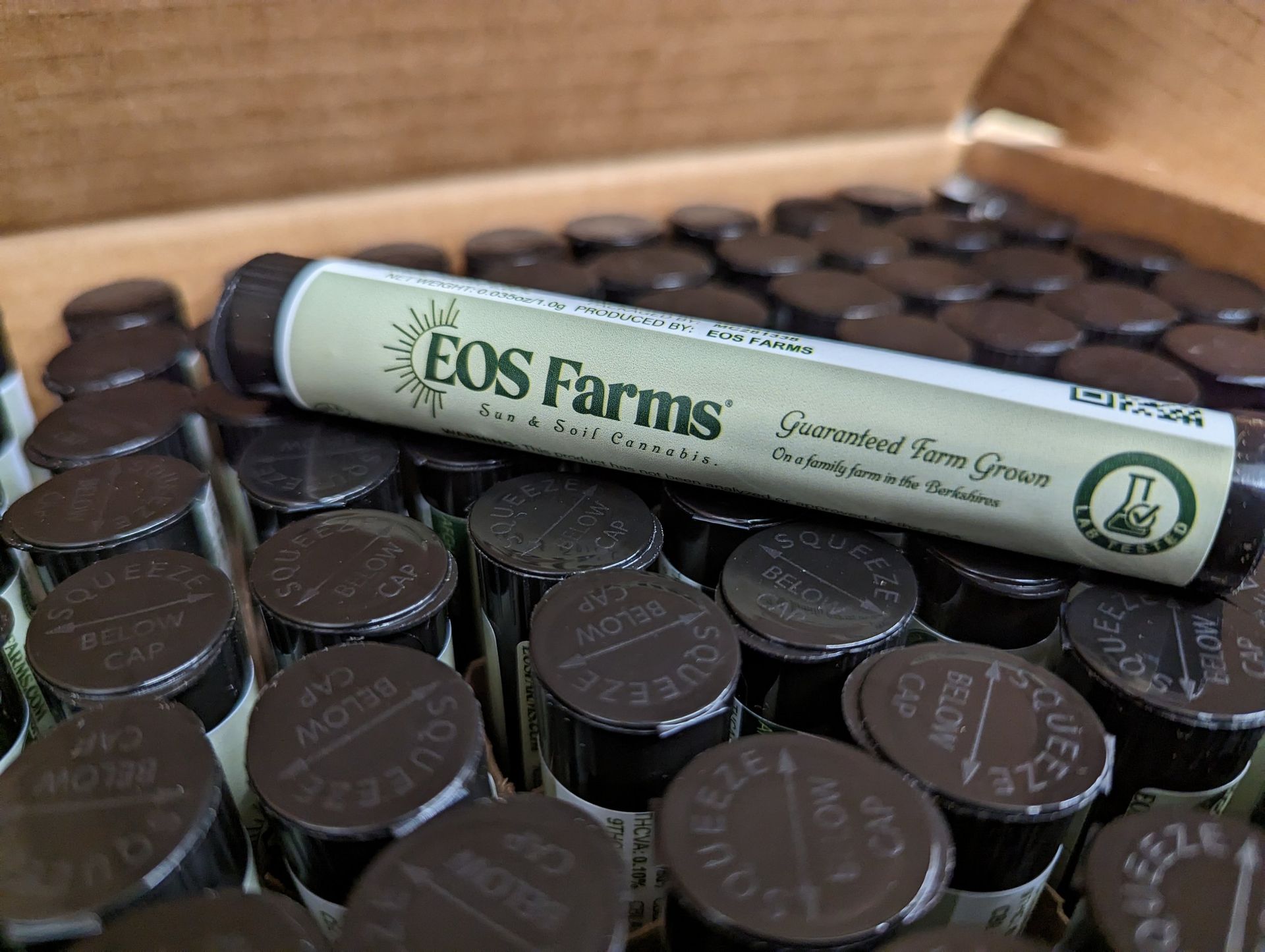 Close-up of tubes of EOS Farms pre-rolls inside a box. One tube rests on top of the others.