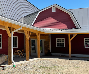 Custom white seamless gutters and downspouts expertly installed on a red timber-framed building.
