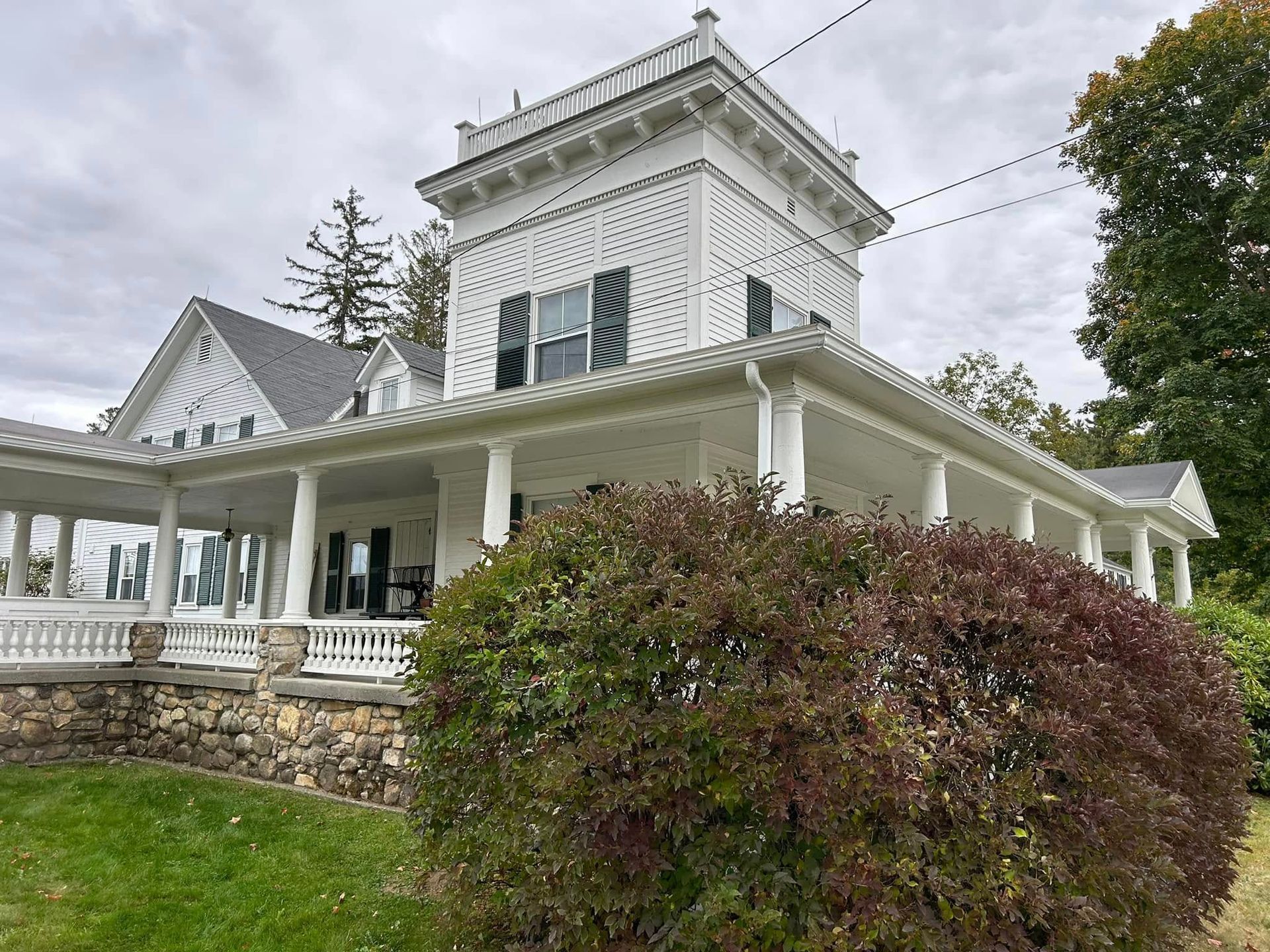 Historic white New England home featuring seamless gutters protected against peak autumn foliage.