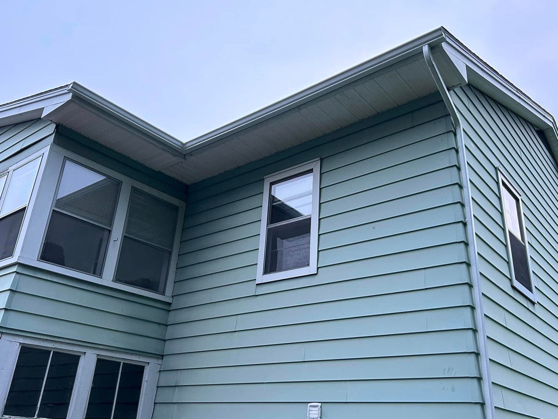A house with white rain gutters, a blue sky in the background