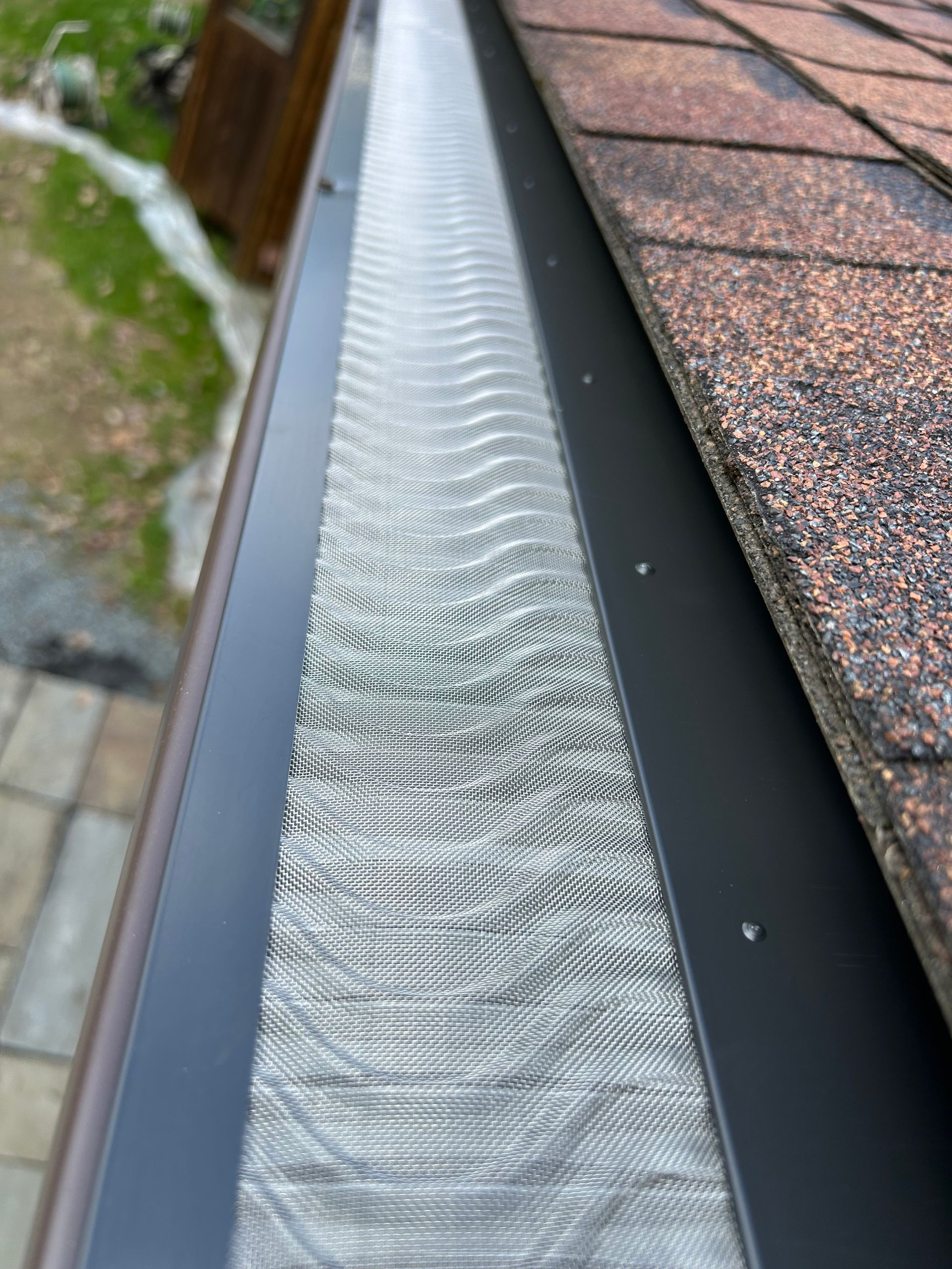 Home with shingles on the roof and gutter guards installed on rain gutters by SNJ.