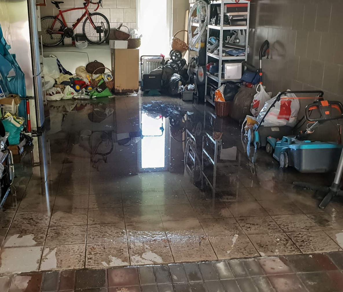 A storage room full of belongings with water on the floor.