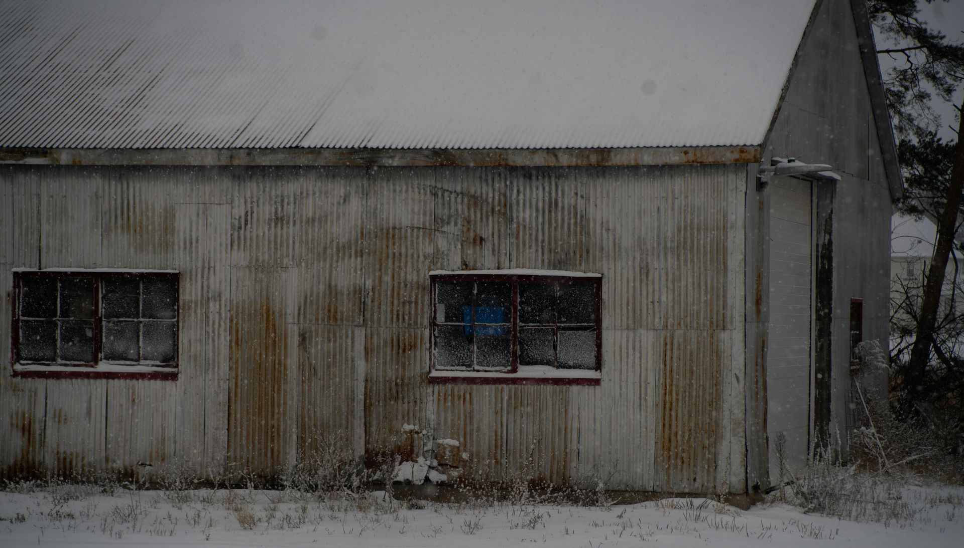A metal-sided building with rust and stains due to the lack of gutters.