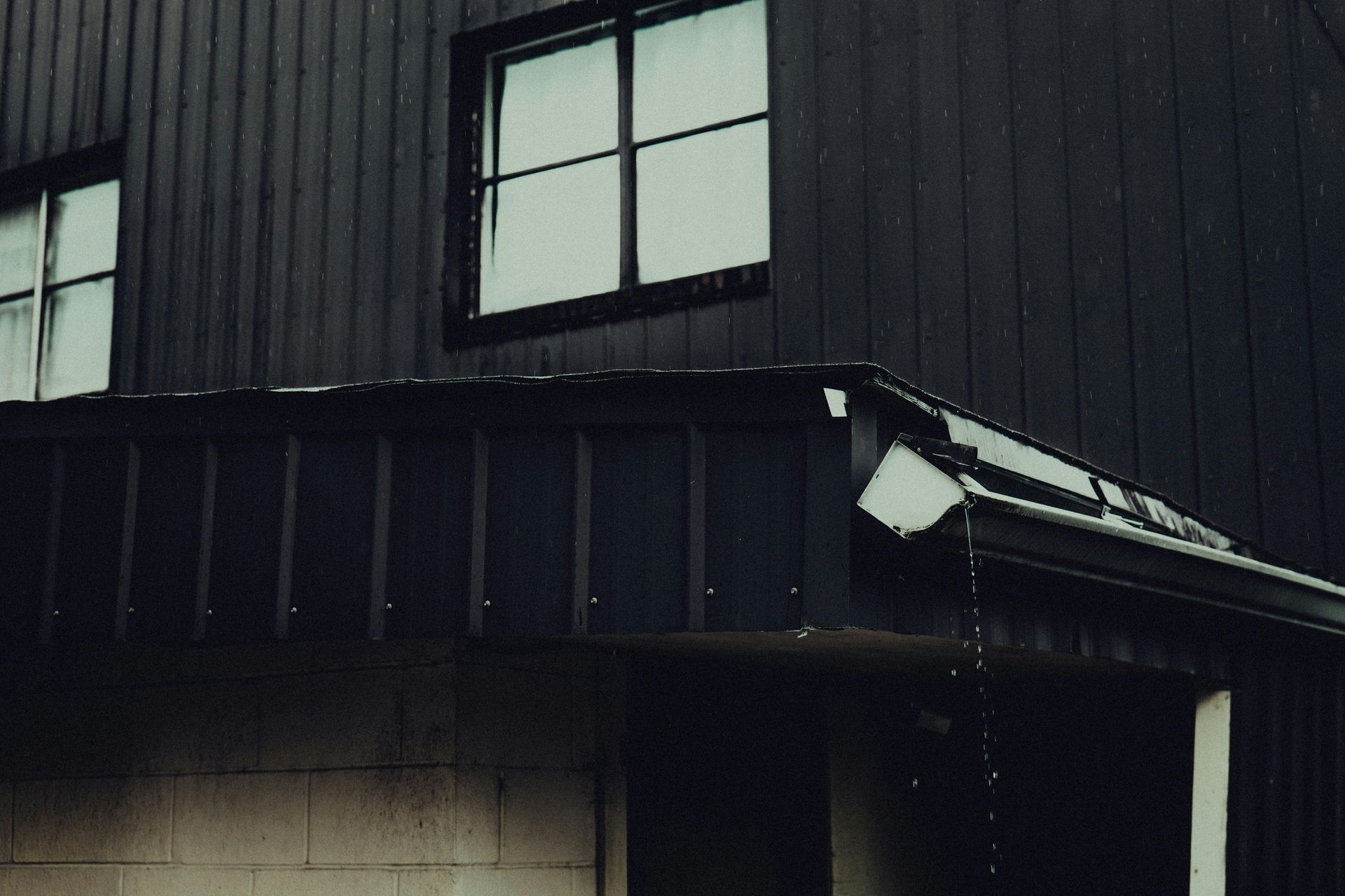 Water overflowing from a broken, sagging traditional gutter during a heavy Vermont downpour.