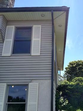 The side of a house with a window and a gutter.