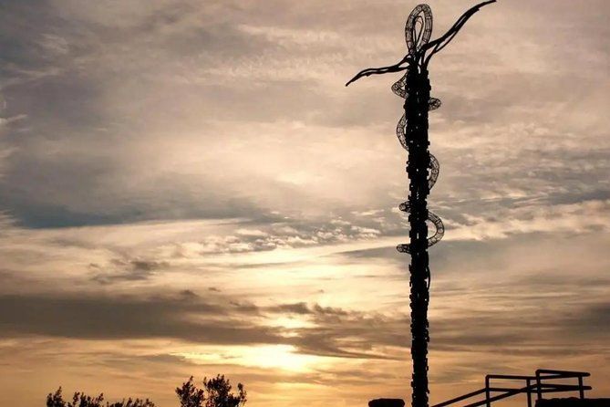 Tall tower silhouetted against an orange sunset sky with scattered clouds