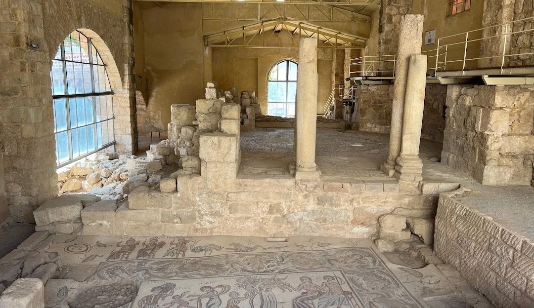Ancient stone interior with arches, columns, and mosaic floor in a historic ruin