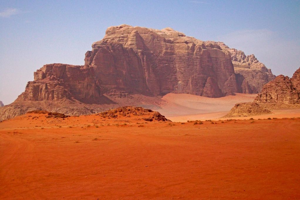 Red desert with a large rocky mesa under a hazy sky